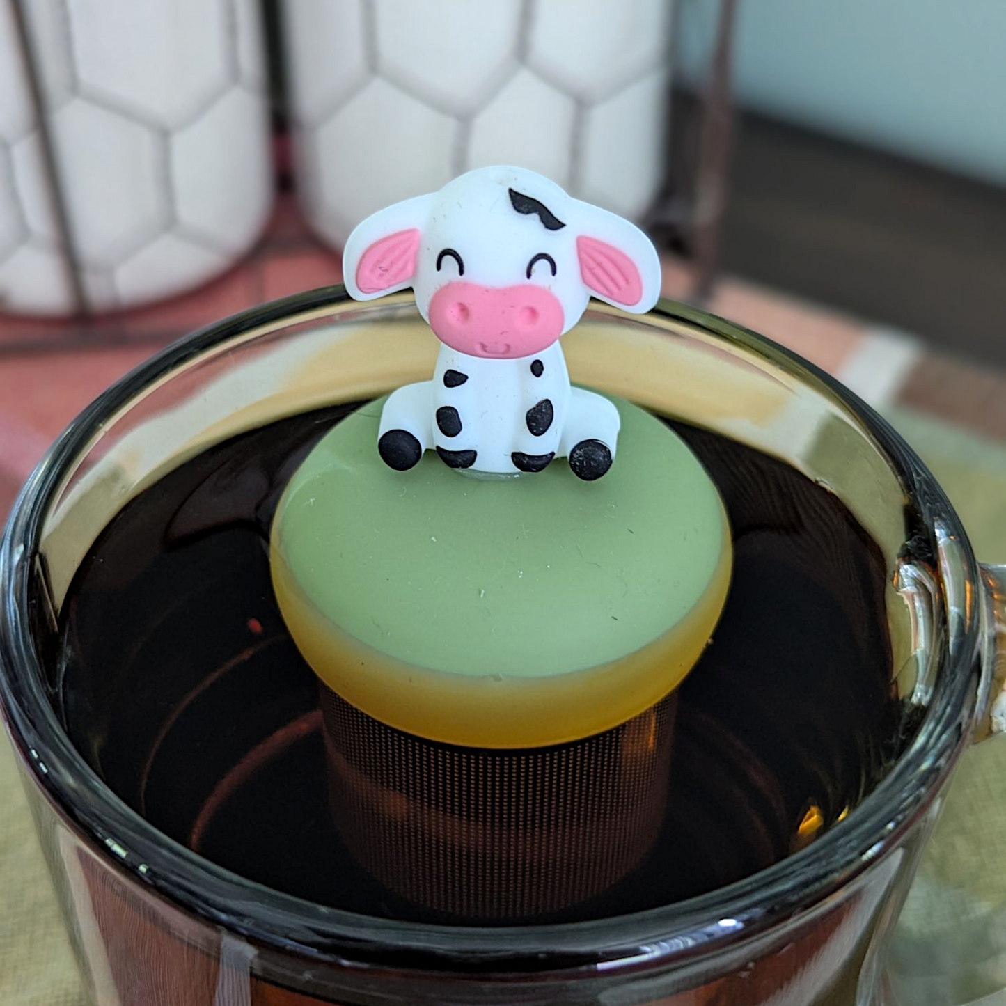 Floating spotted cow tea infuser for loose leaf tea, cute animal-shaped teaware by Float2infuse LLC, showcasing the infuser in a relaxed setting.