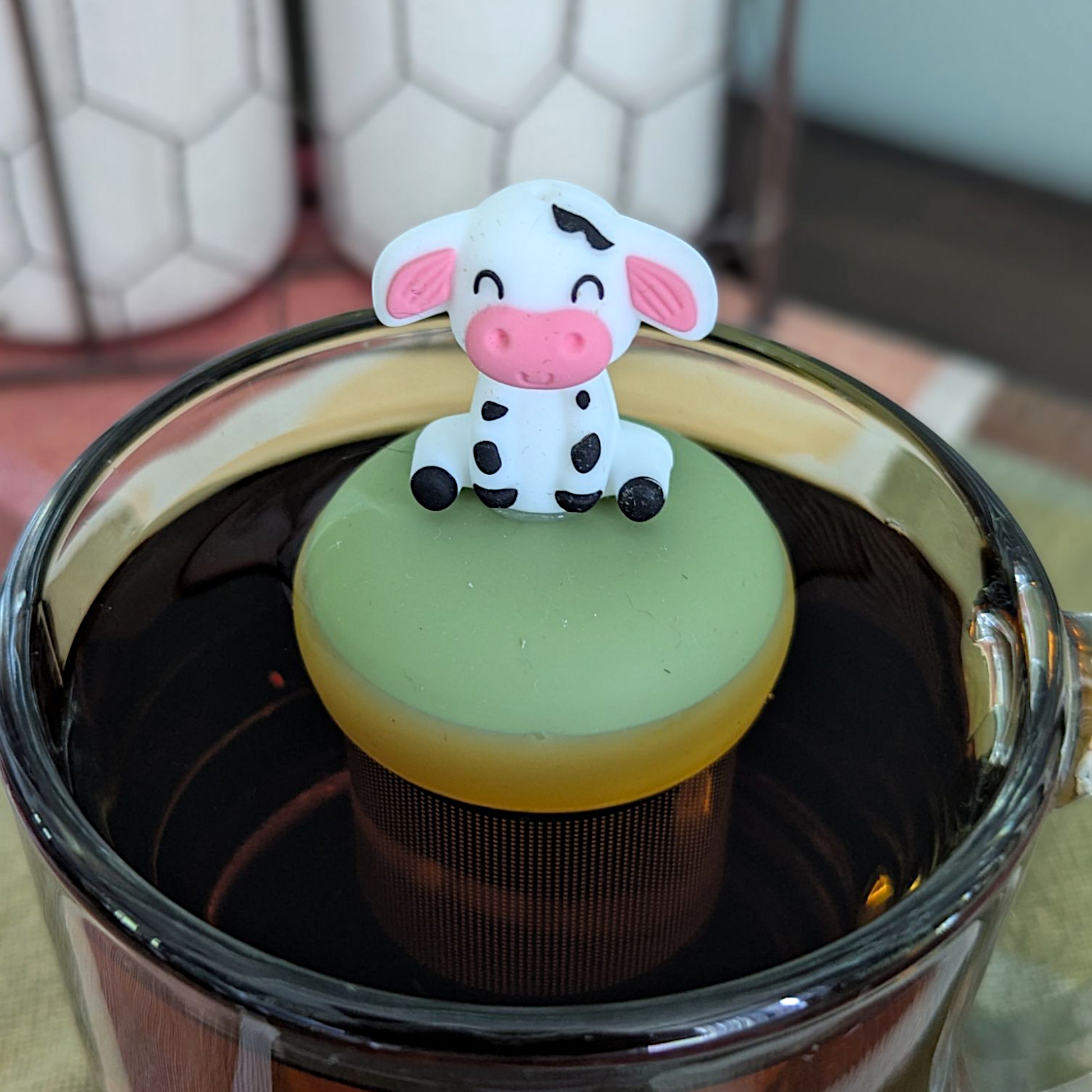 Floating spotted cow tea infuser for loose leaf tea, cute animal-shaped teaware by Float2infuse LLC, showcasing the infuser in a relaxed setting.